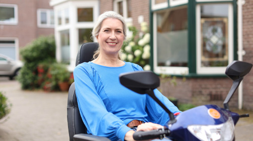 Vrolijk lachende vrouwelijke scootmobielbestuurder op de stoep