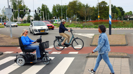 Scootmobielbestuurder, voetganger en fietsers op een rotonde