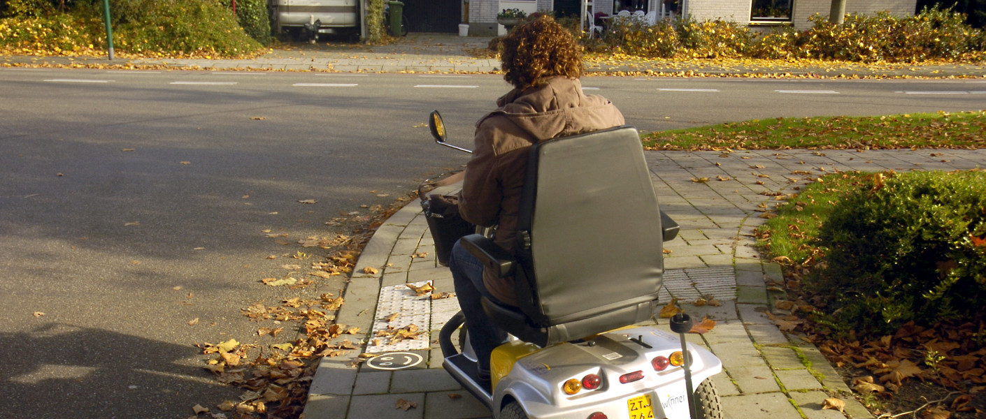 Vrouw rijdt van drempel af met scootmobiel