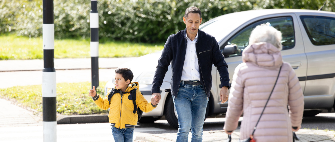 Ouder en kind steken over op een zebrapad met een tegemoetkomende senior met rollator