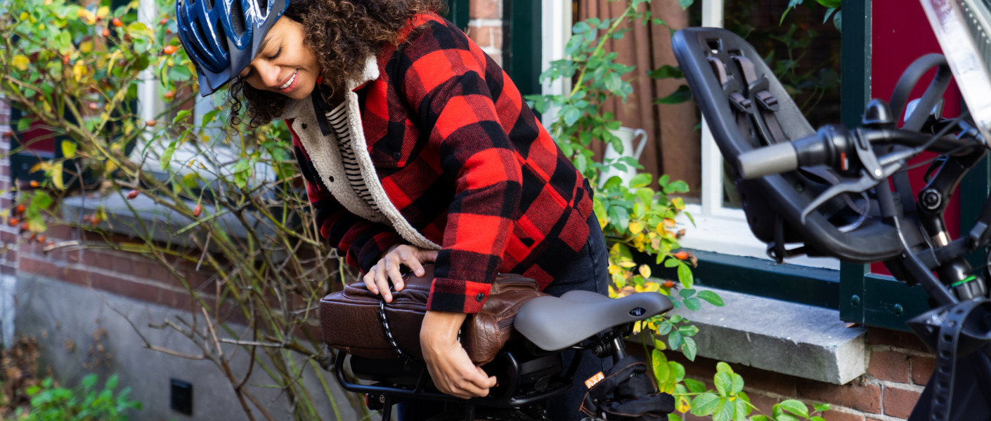 Vrouw die een fietshelm draagt doet haar tas op de snelbinders