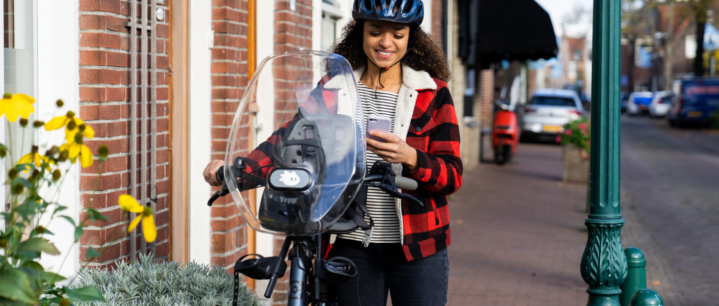 Fietser staat stil op de stoep met telefoon in haar hand