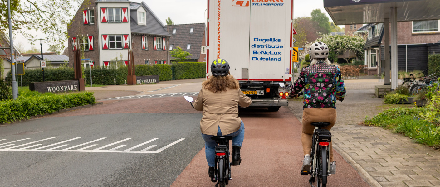Twee fietsers rijden achter en vrachtauto