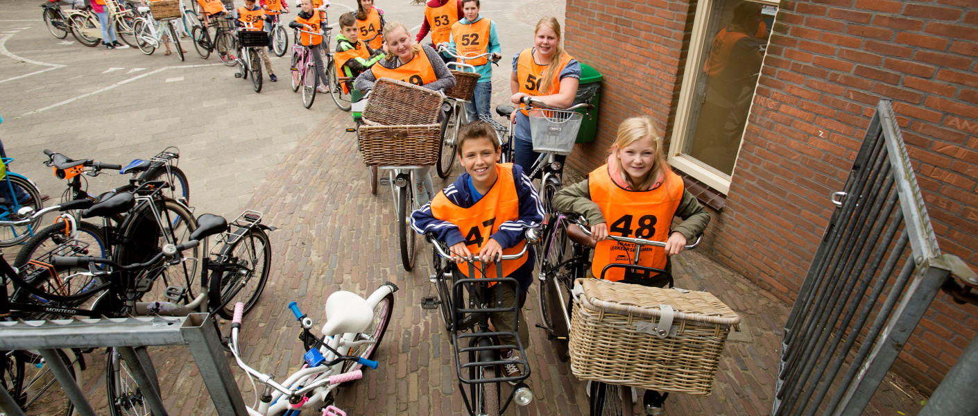 Kinderen met oranje hesjes bij de start van het verkeersexamen