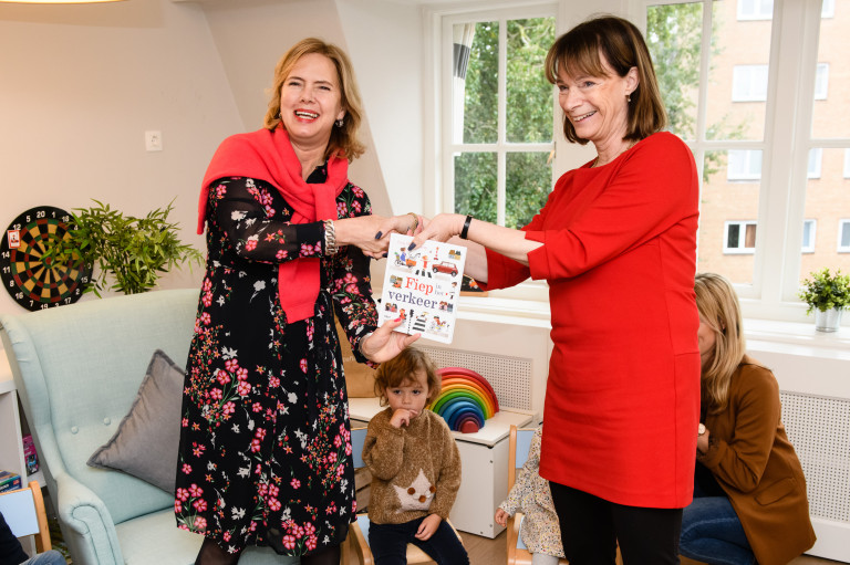 Fiep Westendorp’s curator Gioia Smid overhandigt het vrolijke kinderboek aan minister Cora van Nieuwenhuizen. 