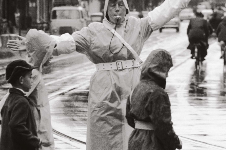 Verkeersbrigadier in 1960 helpt schoolkinderen veilig oversteken op het Paul Krugerplein in Den Haag. 