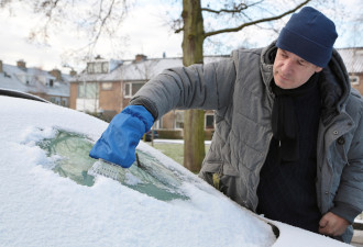 Man haalt de sneeuw en ijzel van zijn auto