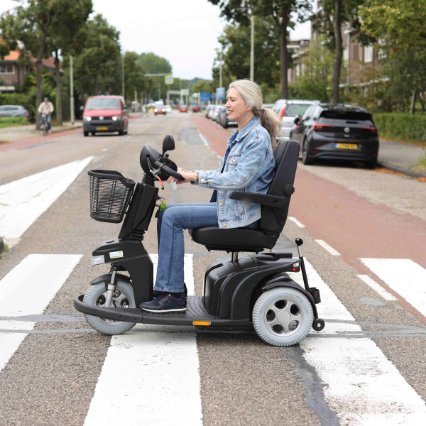 Vrouw op scootmobiel rijdt over zebrapad
